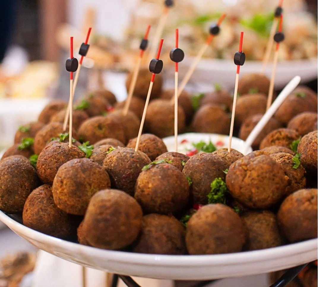 A plate of mini falafel appetizers with skewers and garnished with parsley, perfect for parties.