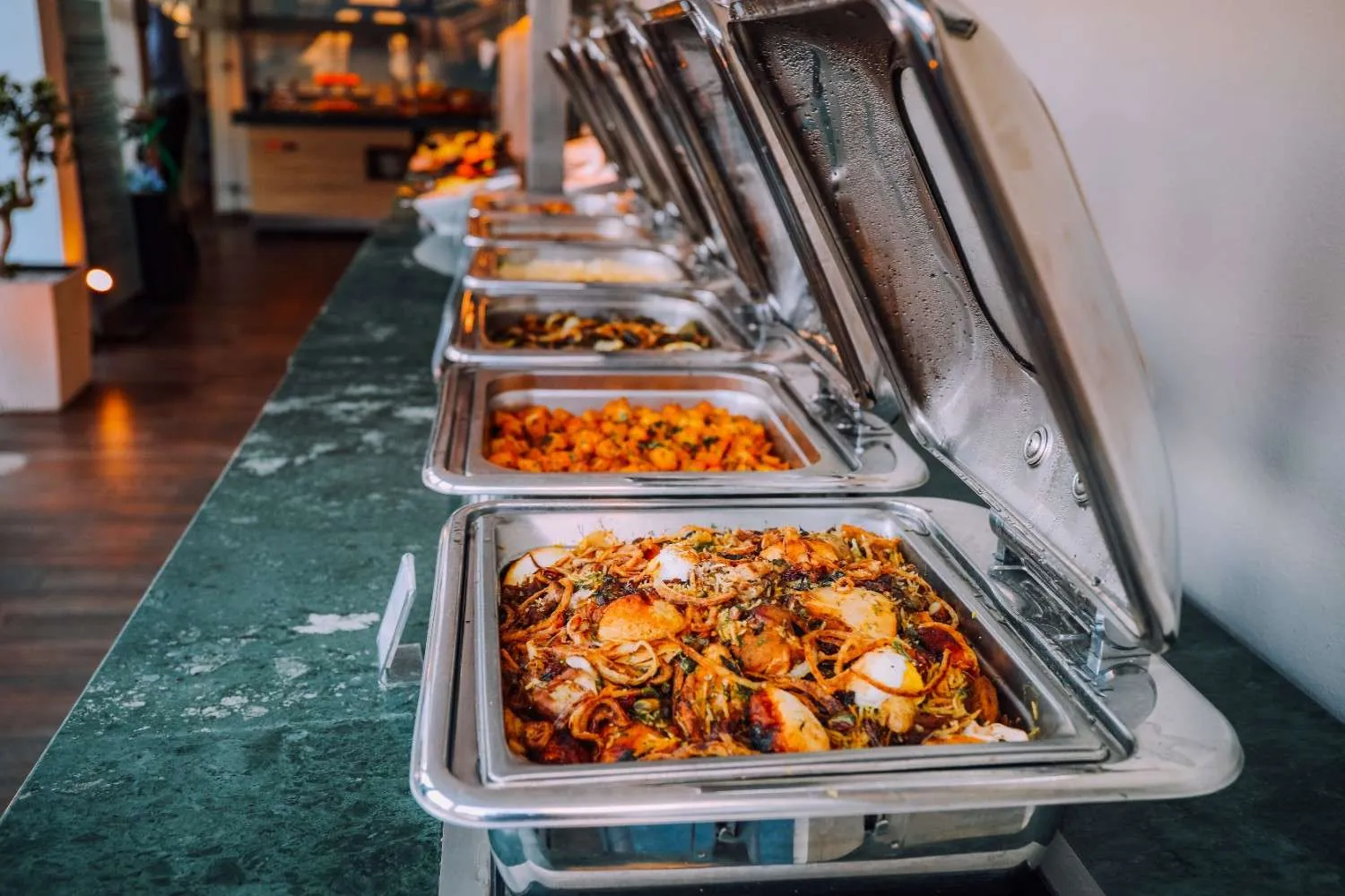 An elegant buffet setup featuring various delicious gluten free dishes in stainless steel chafing dishes.