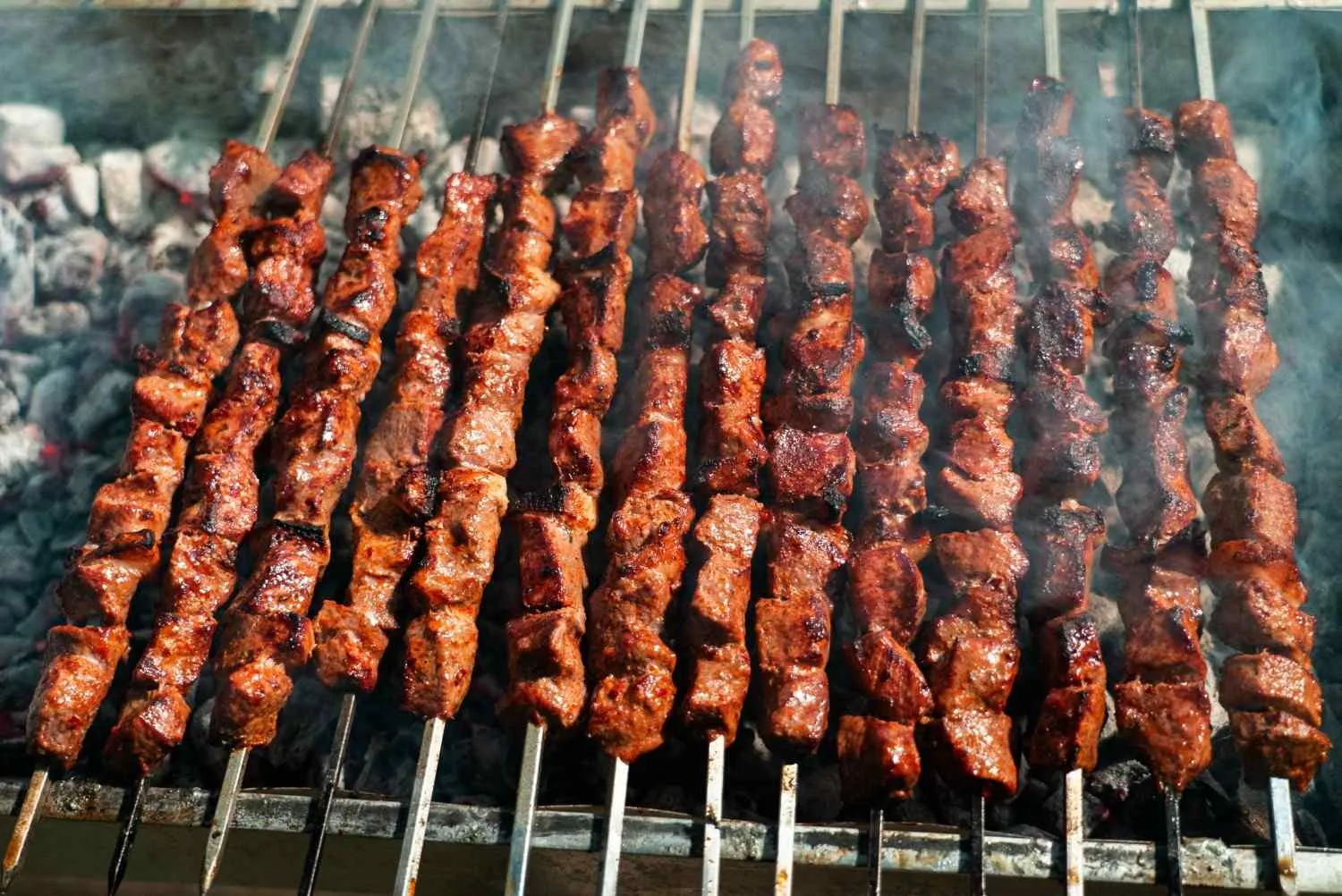 Juicy beef skewers sizzling on an open charcoal grill, perfect for gluten free diners