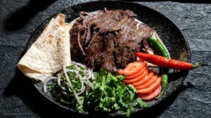 Grilled gyros with fresh vegetables and flatbread on a dark textured background.